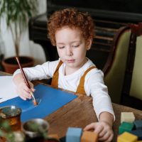 young boy managing emotions by drawing and playing with blocks